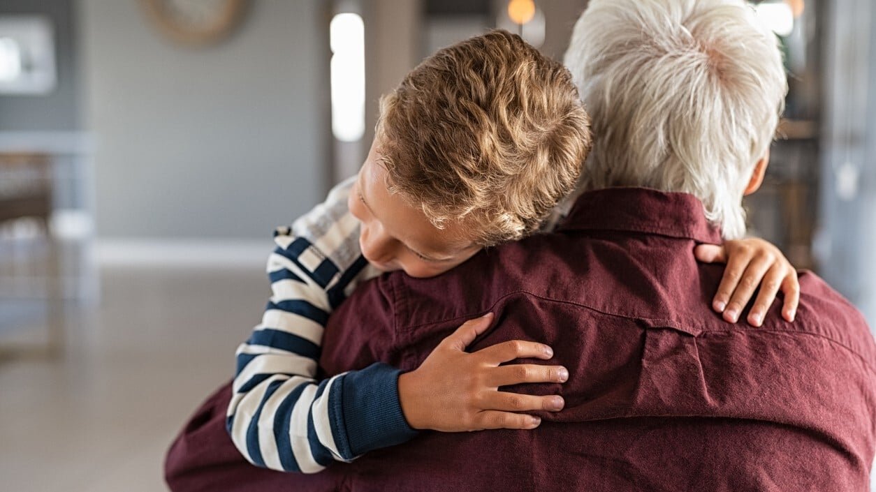 A grandfather being hugged by his grandson.
